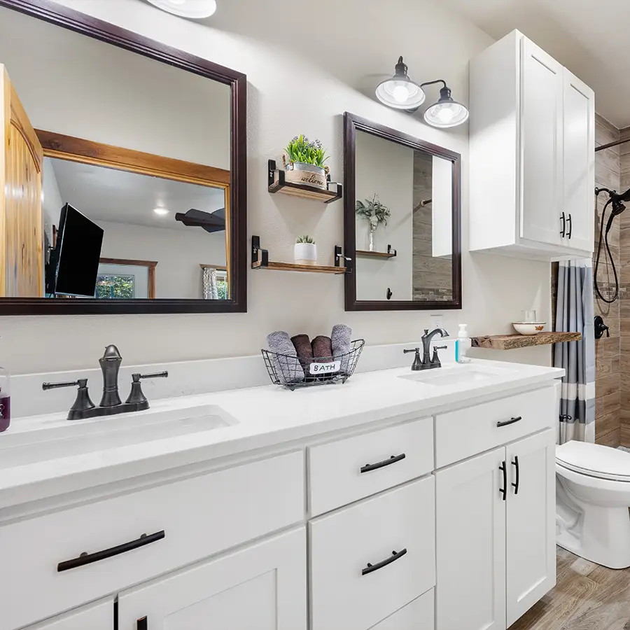 Modern bathroom with white cabinets and double sinks.