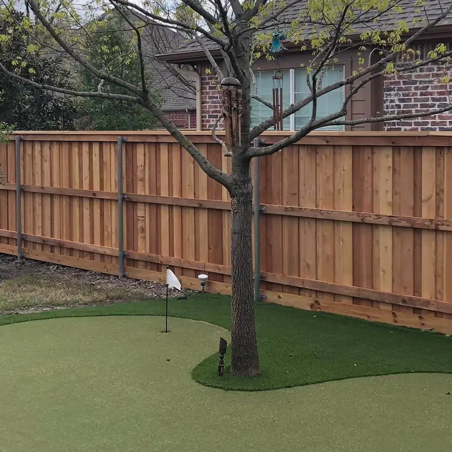 Backyard putting green with custom wooden fence.