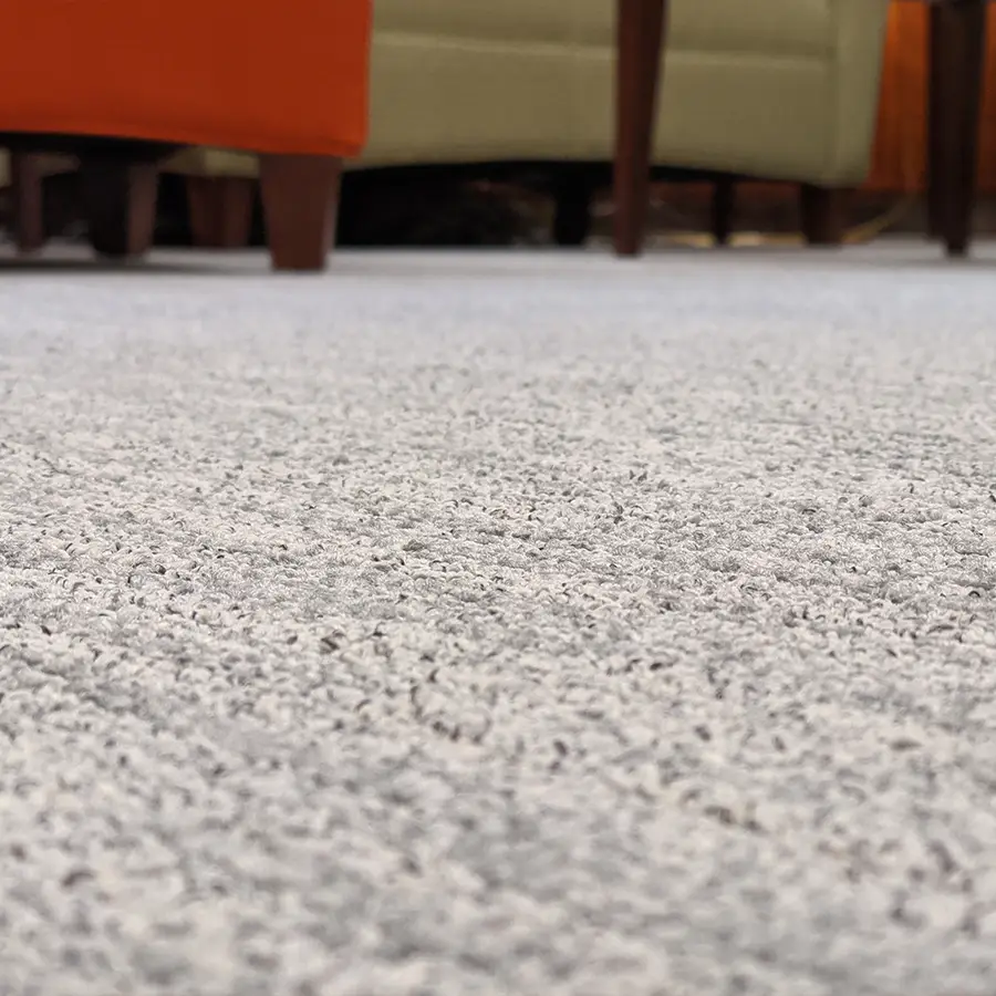 Close-up of textured gray carpet with chairs.