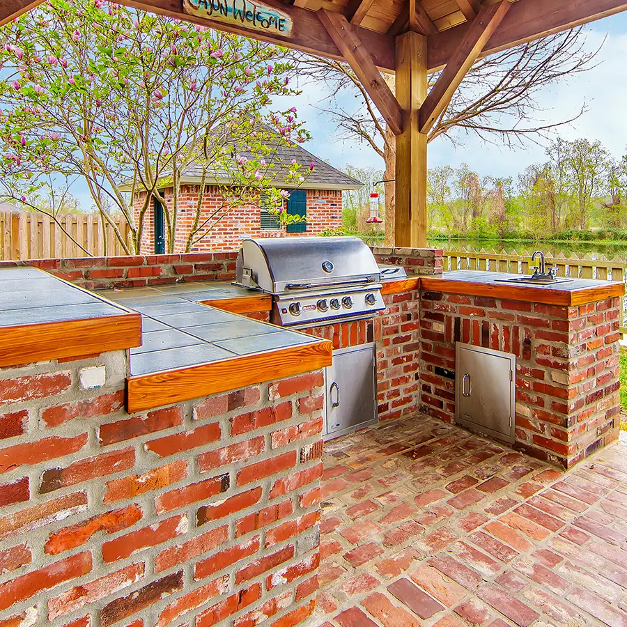 Outdoor brick kitchen with grill and sink.