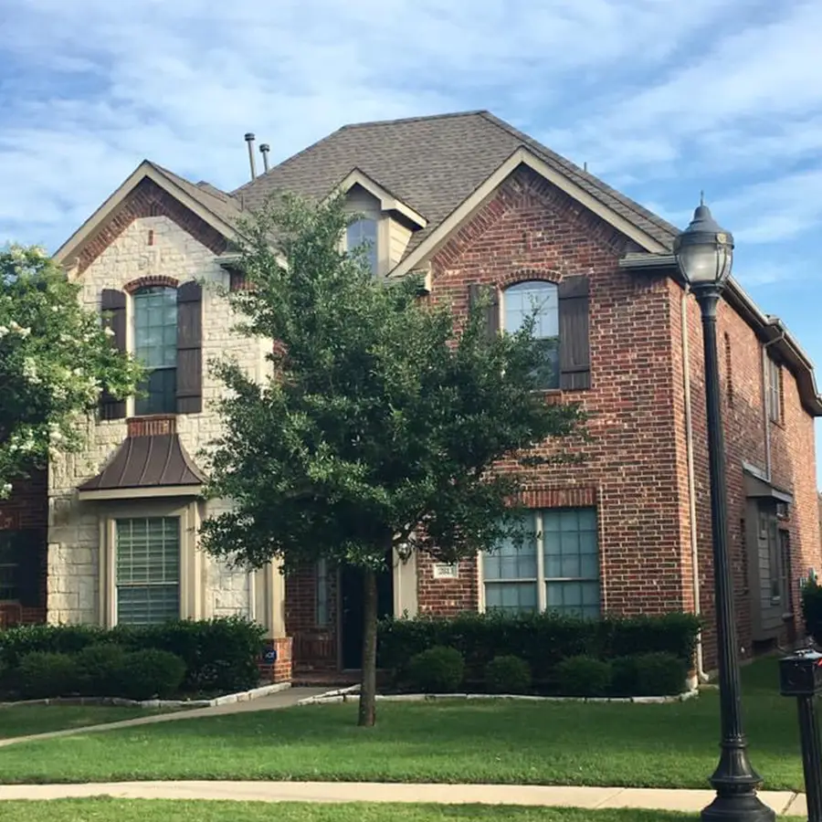 Two-story brick house with tree and lawn and new grey roof