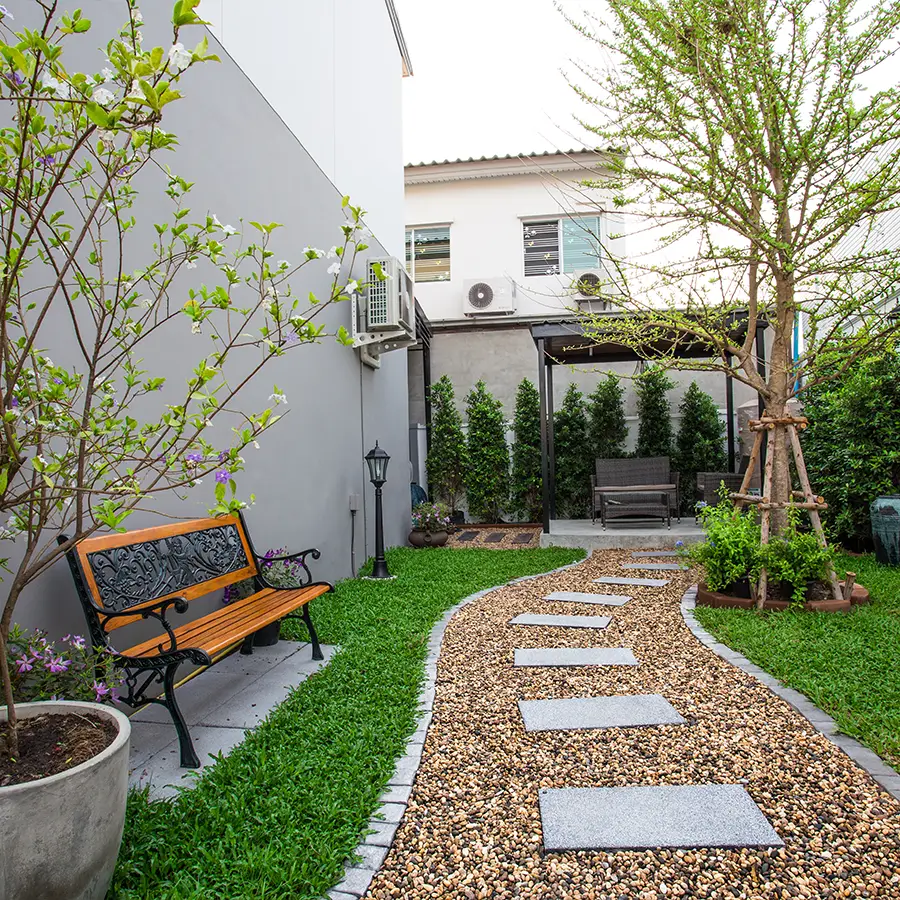 Cozy backyard with bench, trees, gravel walkway.
