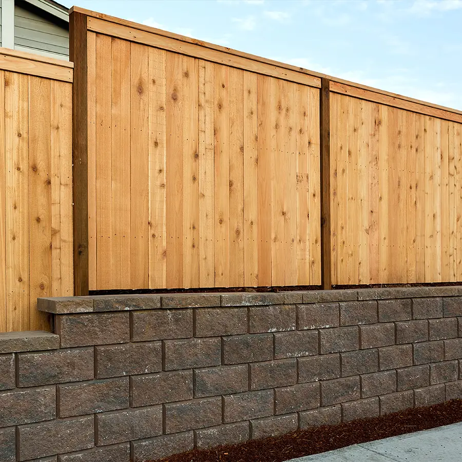 Wooden fence on stone retaining wall, outdoor setting.